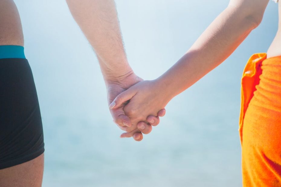 Sección Media De La Pareja Cogidos De La Mano En La Playa Contra El Cielo ·  Foto De Stock Gratuita
